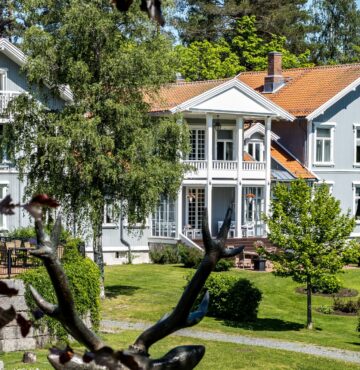 Fronten av Losby Gods. Omgitt av hage og grønne skoger